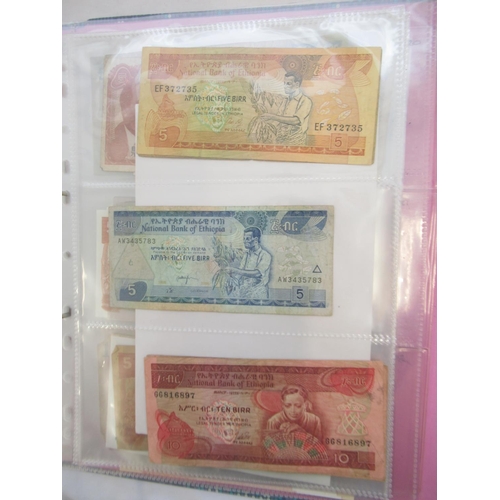 226 - Two folders containing assorted collection of International banknotes from Venezula, Angola, Ghana, ... 