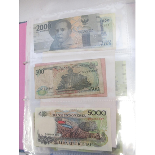 228 - Two folders containing mixed International banknotes from North Korea, Singapore, Indonesia, Malaysi... 