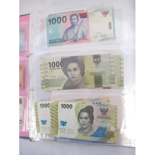 228 - Two folders containing mixed International banknotes from North Korea, Singapore, Indonesia, Malaysi... 