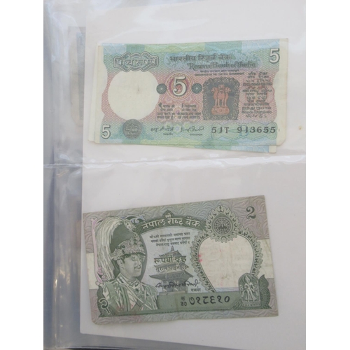 223 - Two folders containing International banknotes from India, Japan, Republic of China, Myanmar, Cambod... 