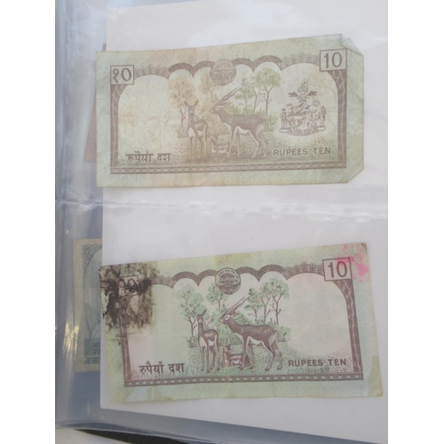 223 - Two folders containing International banknotes from India, Japan, Republic of China, Myanmar, Cambod... 