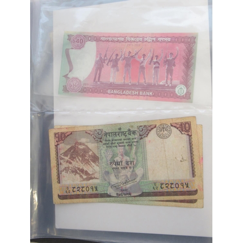 223 - Two folders containing International banknotes from India, Japan, Republic of China, Myanmar, Cambod... 