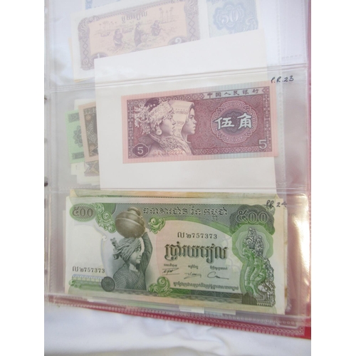 223 - Two folders containing International banknotes from India, Japan, Republic of China, Myanmar, Cambod... 