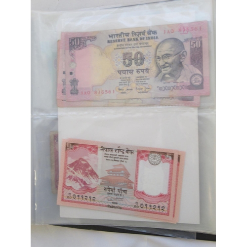 223 - Two folders containing International banknotes from India, Japan, Republic of China, Myanmar, Cambod... 