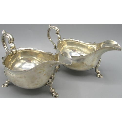 1036 - Pair of George V silver sauce boats with flared pie crust rims, stood on three shell cast hoof feet,... 