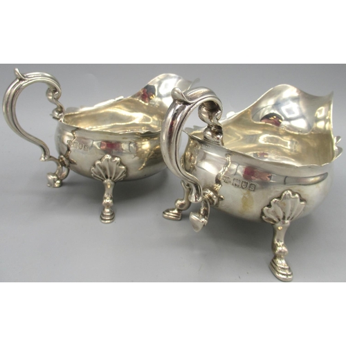 1036 - Pair of George V silver sauce boats with flared pie crust rims, stood on three shell cast hoof feet,... 