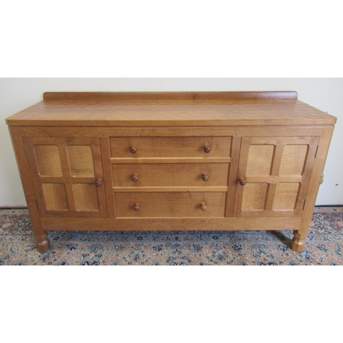 1365 - Robert Mouseman Thompson of Kilburn - a panelled oak sideboard with adzed top above three drawers en... 