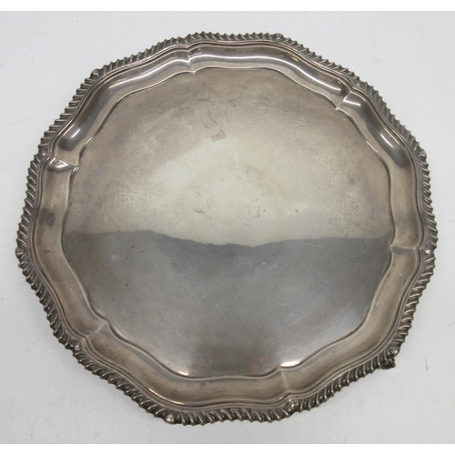 1031 - George V silver shaped circular salver, with raised gadrooned border, on three claw and ball feet, b... 