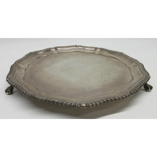 1031 - George V silver shaped circular salver, with raised gadrooned border, on three claw and ball feet, b... 