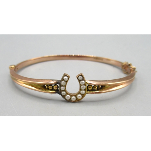 12 - Late Victorian 9ct rose gold hinged bangle with horseshoe design set with seed pearls, 5.63g