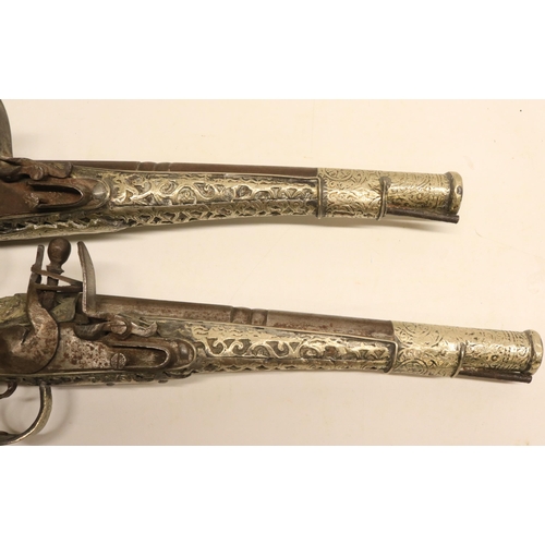 103 - Pair of Balkan silver covered decorative flintlock pistols, 9.5