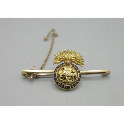 36 - 15ct yellow gold and enamel Northumberland Fusiliers brooch with safety chain, stamped 15ct, 7.46g