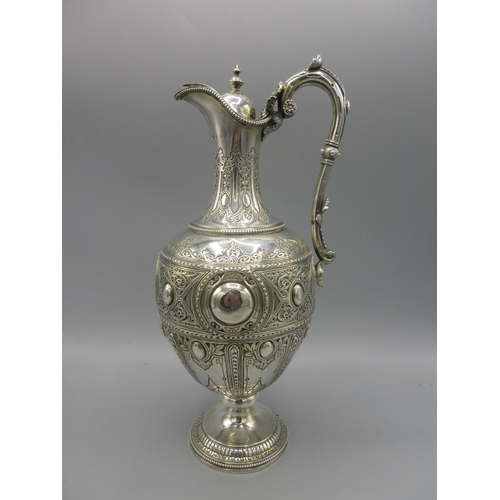 Victorian silver claret jug of baluster form, vacant cartouche, panels of engraved geometric detailing, embossed scrolling and foliate design, urn finial and leaf clasped scroll handle, by Matin, Hall & Co, London 1875, 20.85ozt