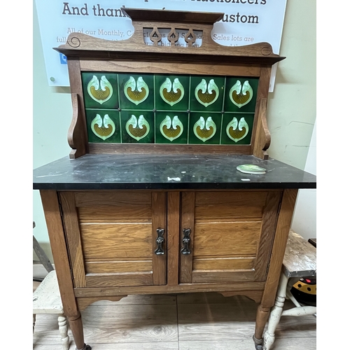 751 - Edwardian oak washstand, black marble top with Art Nouveau tiled back above two doors on turned supp... 