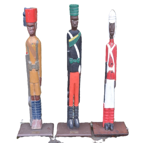 144 - Three large hand carved wooden soldier figures depicting British African soldiers at attention, all ... 