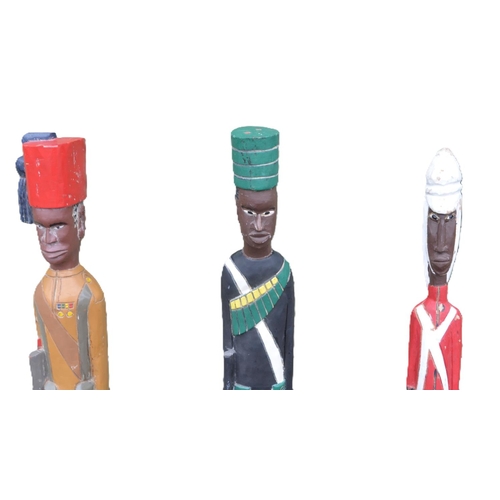 144 - Three large hand carved wooden soldier figures depicting British African soldiers at attention, all ... 