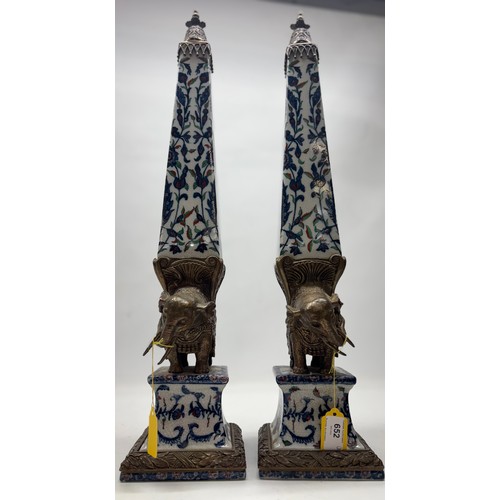 652 - Pair of Wong Lee ceramic obelisks with bronzed metal mount in the shape of an elephant, H61cm