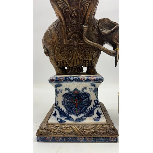 652 - Pair of Wong Lee ceramic obelisks with bronzed metal mount in the shape of an elephant, H61cm