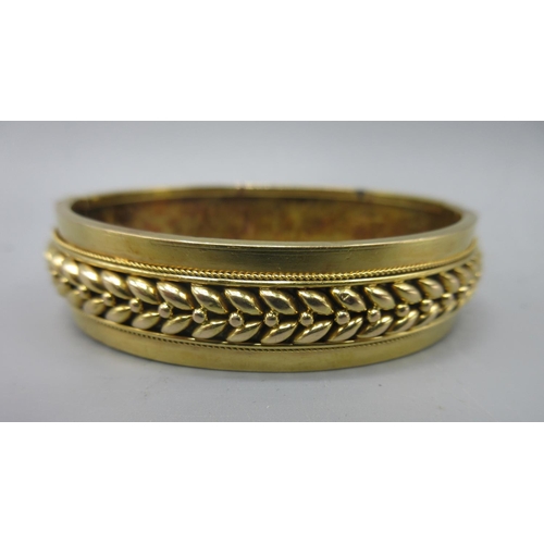 2 - Yellow metal hinged bangle with Etruscan style detail, 13.58g