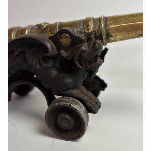 758 - Large Victorian brass model table cannon on mounted cast iron carriage with dragons either side