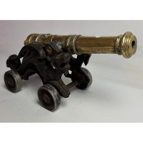 758 - Large Victorian brass model table cannon on mounted cast iron carriage with dragons either side