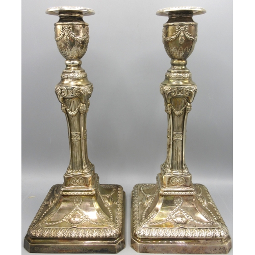 Pair of 20th C silver candlesticks with gadrooned sconces decorated with ribbon swags above square tapered columns having rams head masks to the edges leading to a square base adorned with urn and foliate swag repousse, by Barker Ellis Silver Co, Birmingham 1973, core and base loaded, H31cm