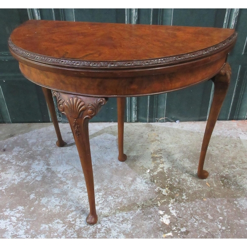 570 - Geo. 111 style figured walnut demi-lune card table, folding top on shell and scroll carved cabriole ... 