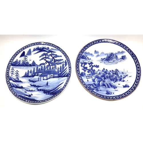 1156 - Pair of 20th century Japanese circular chargers, blue & white painted with figures and pagoda in lan... 