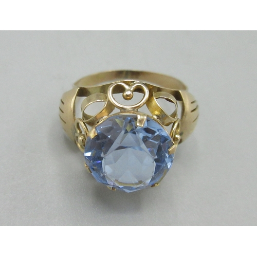 1052 - Yellow metal cocktail ring, large blue stone set in ornate mount, marks indistinct, size Q, 3.9g

Br... 