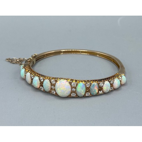 1004 - 19th century 18ct yellow gold opal and diamond hinged bangle, decorated with a row of eleven graduat... 