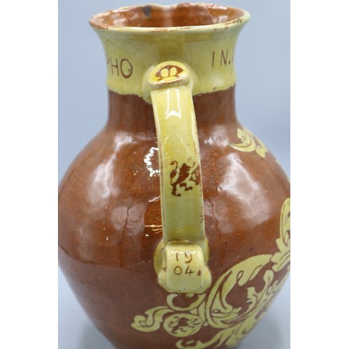 1060 - North Devon slipware harvest jug, scrolled handle, inscribed 'IN VERITATE TRIUMPHO', dated 1904, H24... 