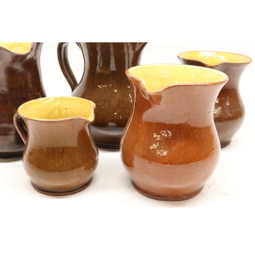 1029 - Five Yorkshire slipware jugs, yellow internal glaze, of varying sizes, in the manner of Isaac Button... 