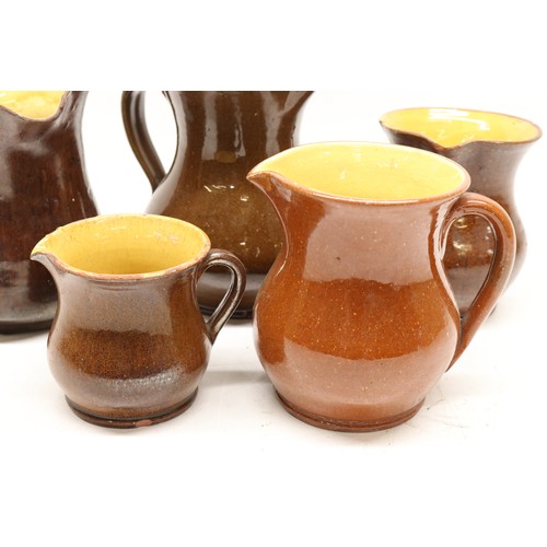 1029 - Five Yorkshire slipware jugs, yellow internal glaze, of varying sizes, in the manner of Isaac Button... 