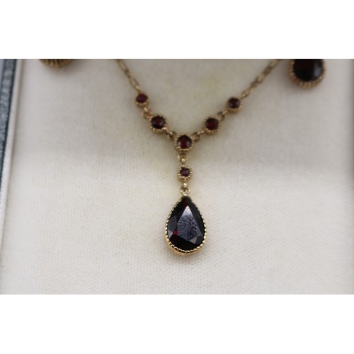 10 - Stamped 9ct yellow gold garnet pendant and earrings set, comprising a hallmarked 9ct seven-stone gar... 