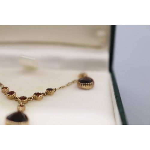 10 - Stamped 9ct yellow gold garnet pendant and earrings set, comprising a hallmarked 9ct seven-stone gar... 