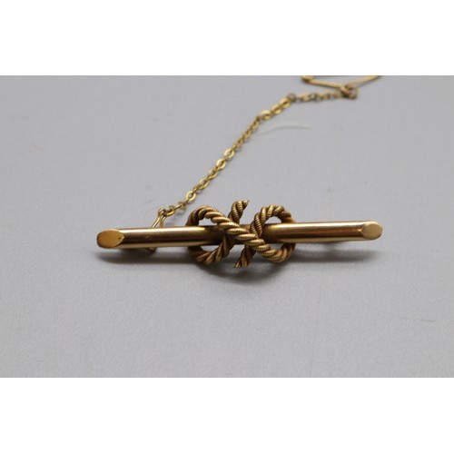 24 - A stamped 15ct yellow gold bar brooch with intertwined rope embellishment and safety chain. Total we... 