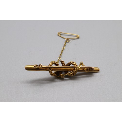 24 - A stamped 15ct yellow gold bar brooch with intertwined rope embellishment and safety chain. Total we... 