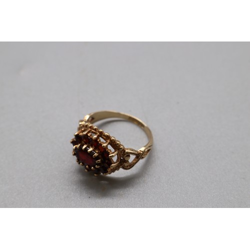 31 - A hallmarked 9ct yellow gold garnet cluster cocktail ring, Birmingham assay 1973–1974, with an inter... 