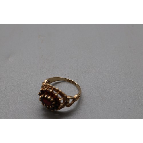 31 - A hallmarked 9ct yellow gold garnet cluster cocktail ring, Birmingham assay 1973–1974, with an inter... 