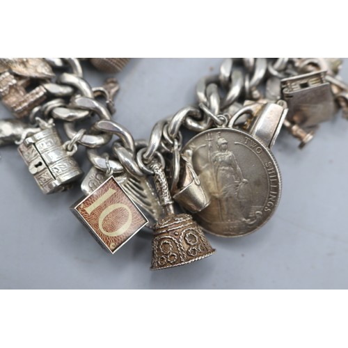 24 - Large, heavy charm bracelet comprising a thick-gauge solid curb link hallmarked sterling silver brac... 
