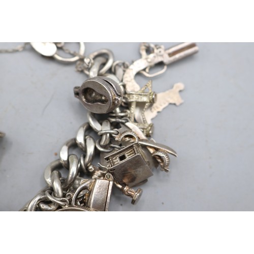 24 - Large, heavy charm bracelet comprising a thick-gauge solid curb link hallmarked sterling silver brac... 