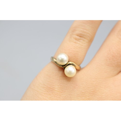 23 - Stamped 9ct yellow gold pearl toi et moi ring, comprising two 6mm pearl beads set to offset twisted ... 