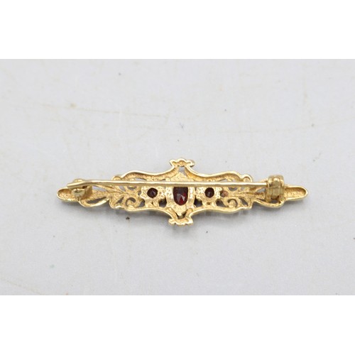 58 - Hallmarked 9ct yellow gold garnet three-stone bar brooch, comprising one central oval-cut faceted ga... 