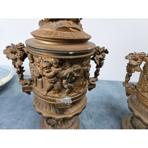 305 - Highly ornate cast & gilt metal urn with lift off lid and cherubs