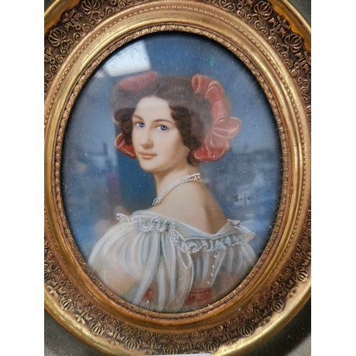 715 - Antique miniature portrait of a lady. Bow in her hair and pearls. In gold gilt and velvet frame.