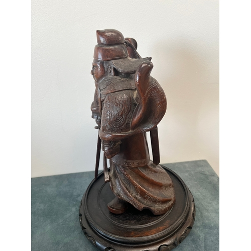 160 - Chinese carved hardwood model of a warrior. On a hardwood stand