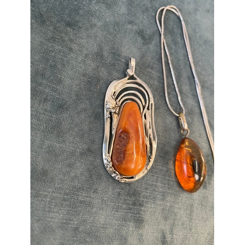 512 - Amber pendant with an internal bug on a silver chain and a silver and natural amber necklace pendant... 