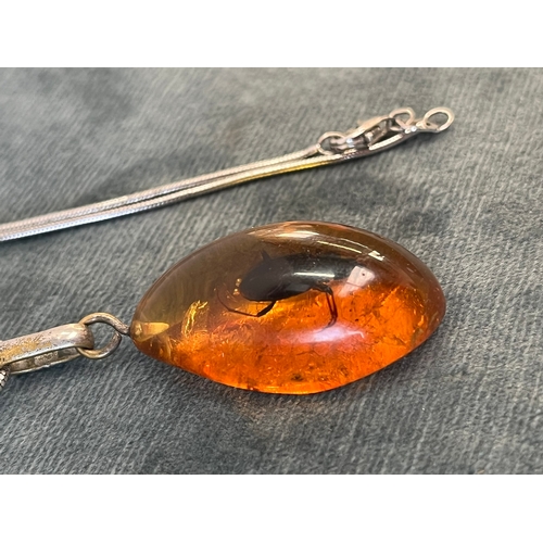 512 - Amber pendant with an internal bug on a silver chain and a silver and natural amber necklace pendant... 