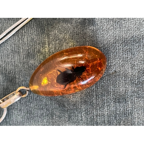 512 - Amber pendant with an internal bug on a silver chain and a silver and natural amber necklace pendant... 