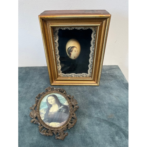 296 - Cased painted egg and reproduction of Mona Lisa in brass frame